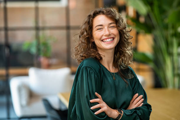 istockphoto-1289220545-612×612 Portrait of young smiling woman looking at camera with crossed arms. Happy girl standing in creative office. Successful businesswoman standing in office with copy space.